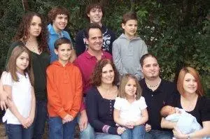 A big family photo outdoors: Dr. Holmes with his wife, children and grandchildren, the youngest a baby in a blanket